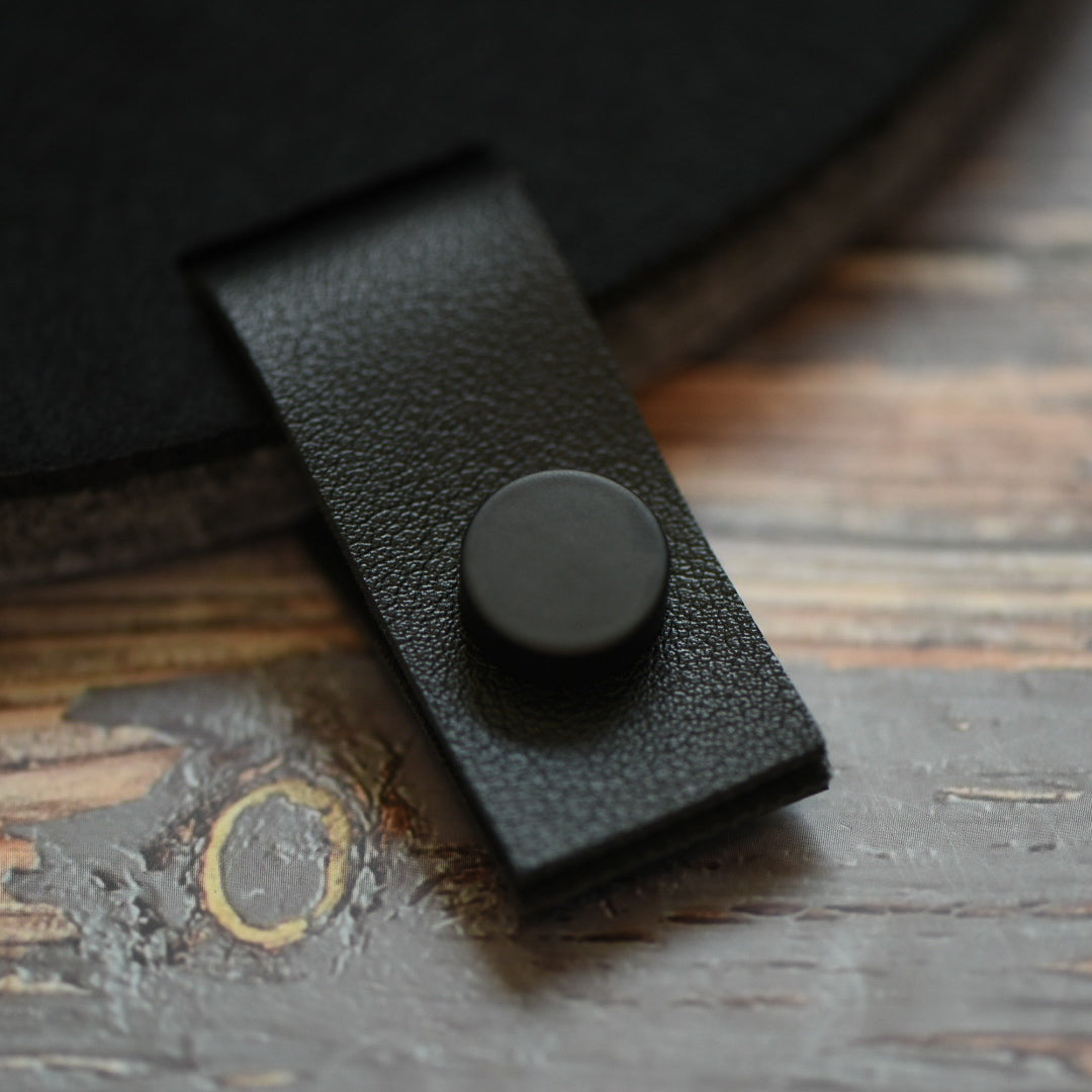 Faux leather black tab with black button attached to a felt board