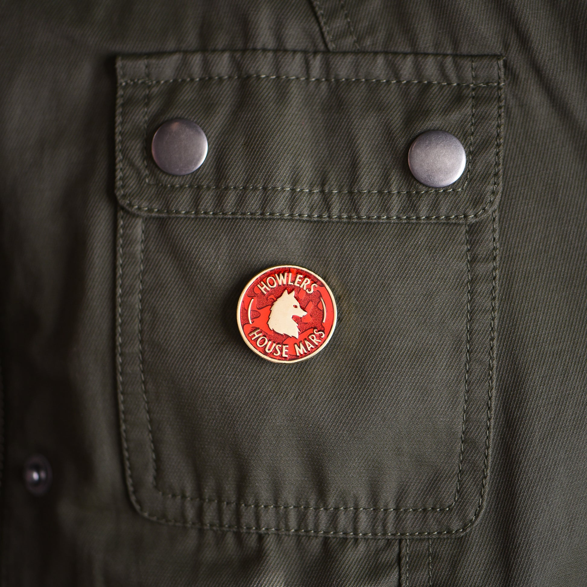 Red and gold circle membership style enamel pin with a wolf and howler house mars text