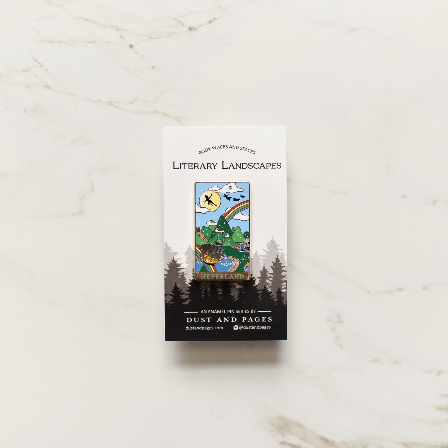 Gold Neverland landscape enamel pin with rainbow, moon, peter pan silhouette, and fairy ship details on an open book