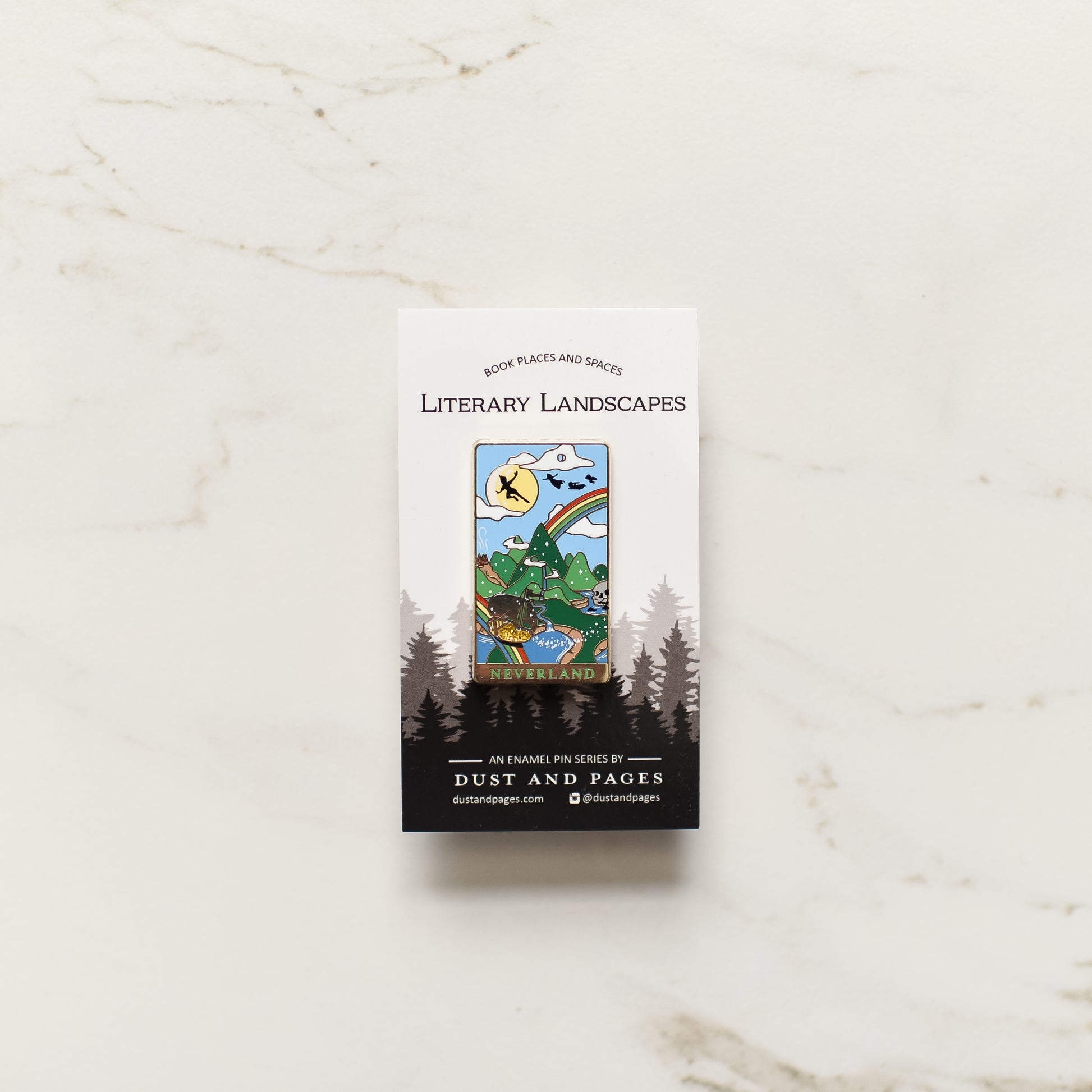 Gold Neverland landscape enamel pin with rainbow, moon, peter pan silhouette, and fairy ship details on an open book