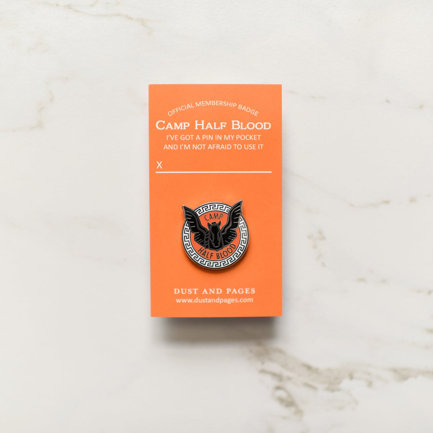 Blackjack horse with black mane and wings inside an orange and black circle enamel pin on an orange backing card