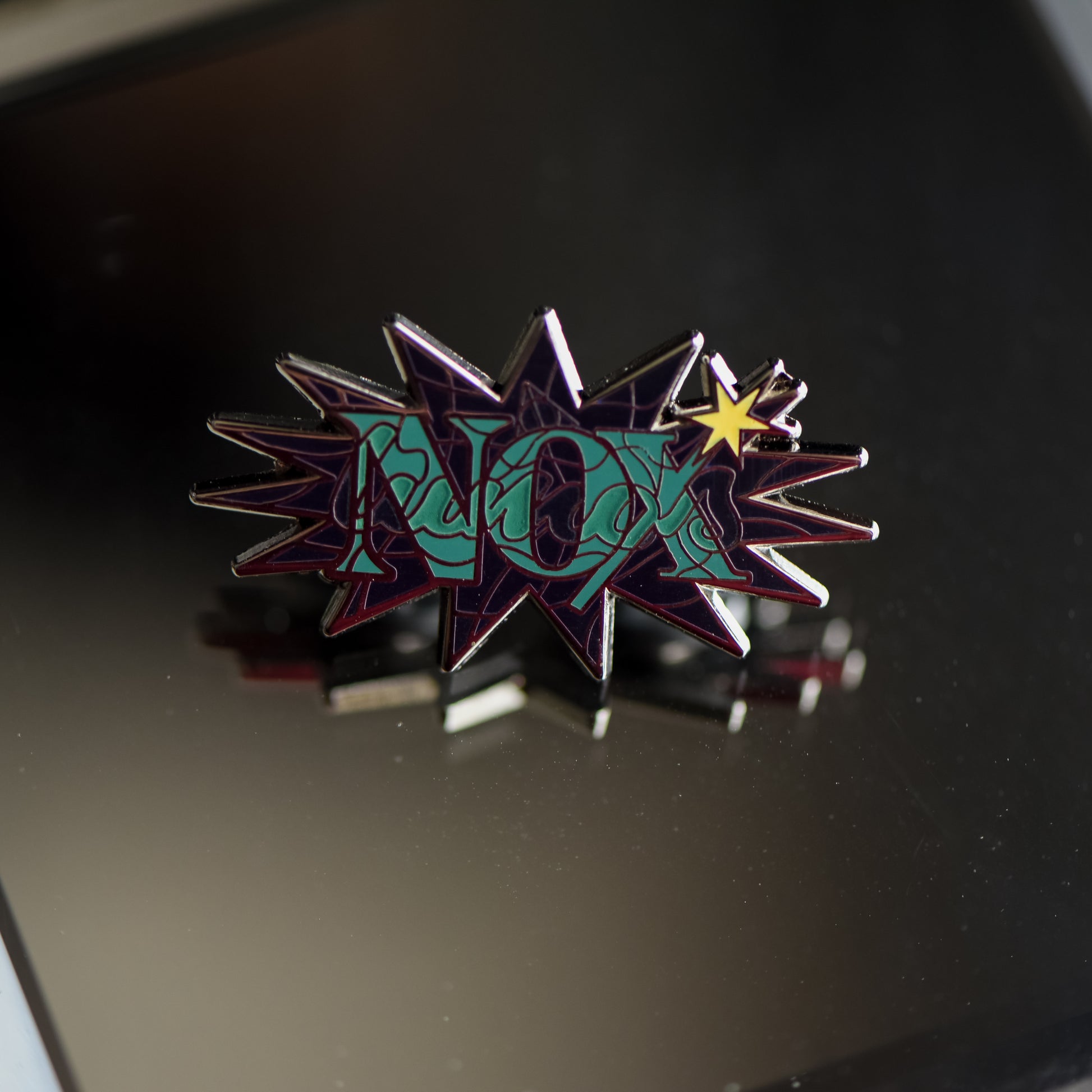 Black nickel enamel pin with Nox in green letters with glow in the dark lumos letters on a potion spell book