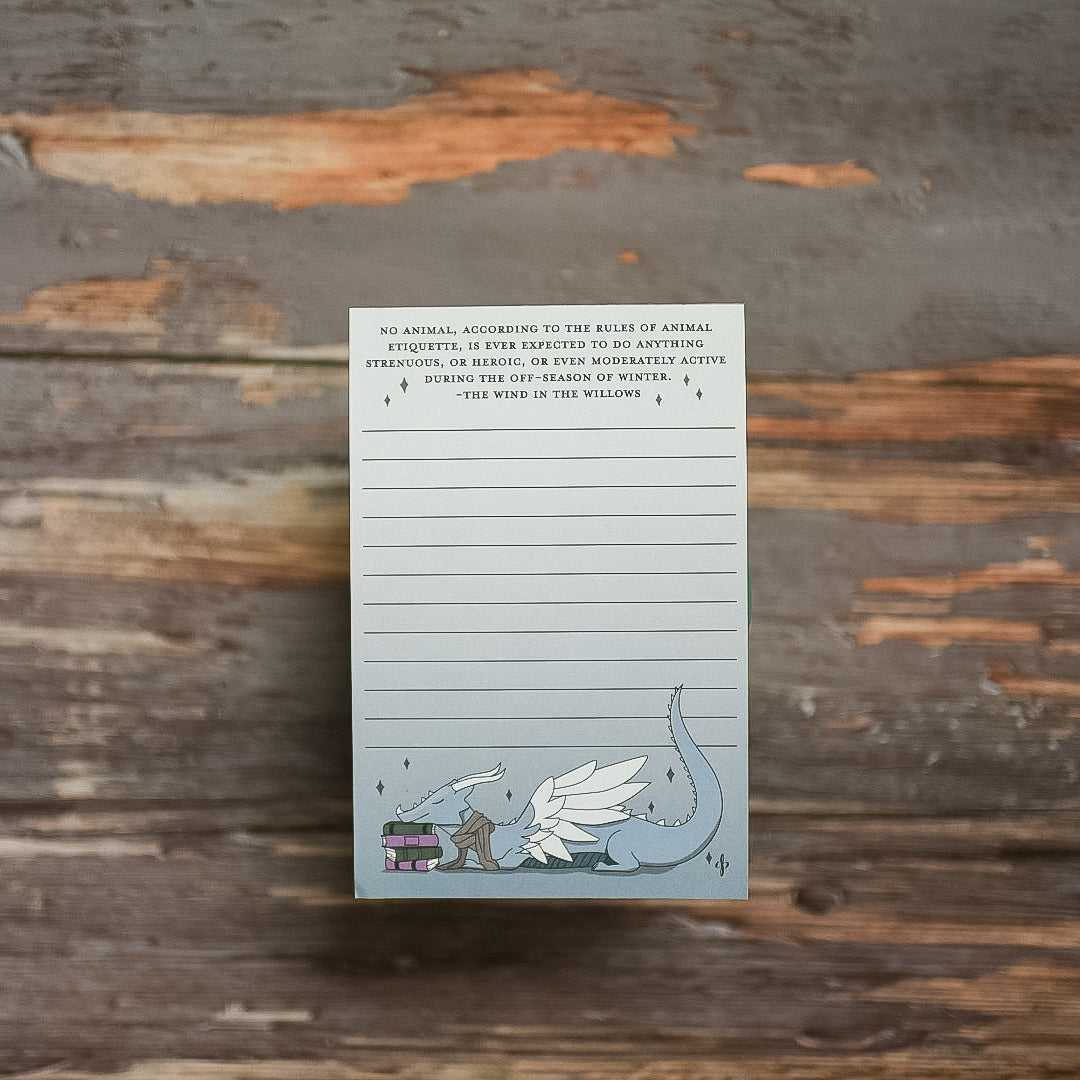 Notepad with kawaii blue dragon sleeping on a stack of books