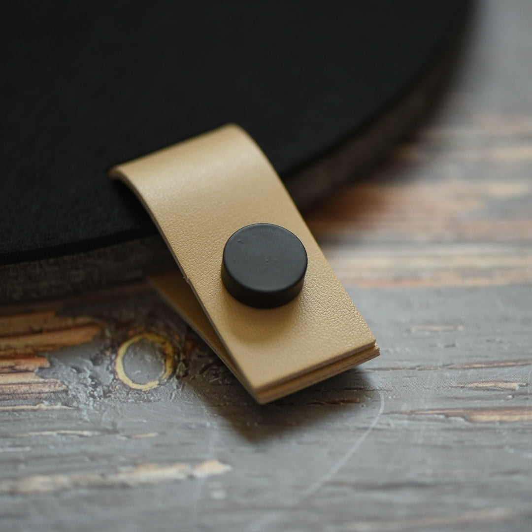 Faux leather cream tab with black button attached to a felt board