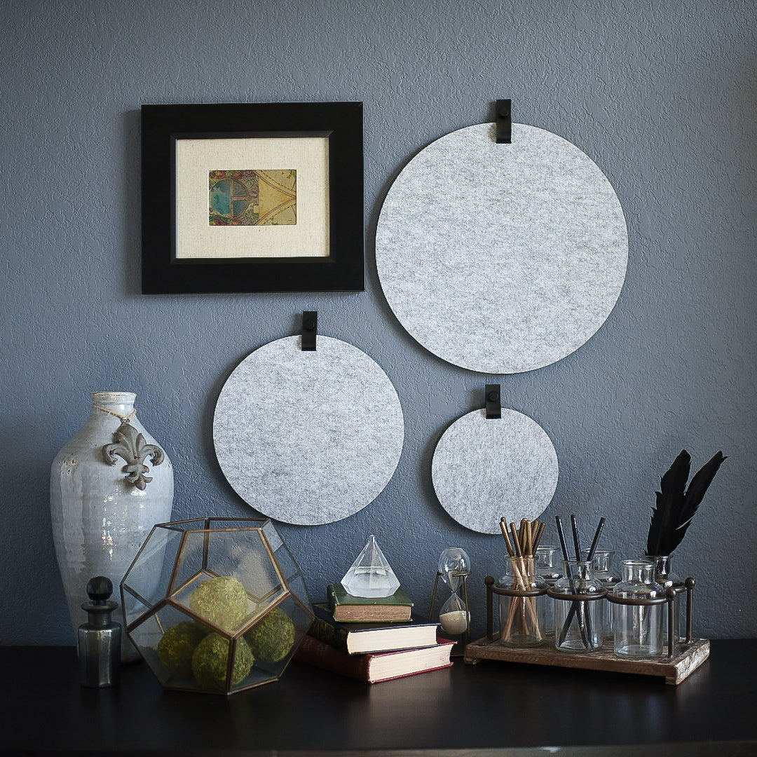 Three round gray felt boards with black tabs hanging on an office wall