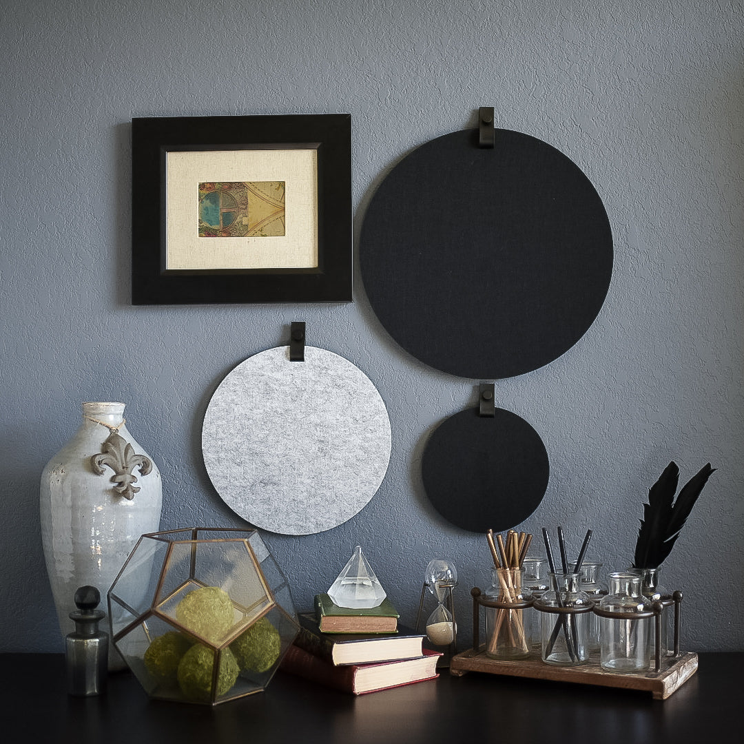 Three round felt boards for organization with black tabs hanging on a cozy wall