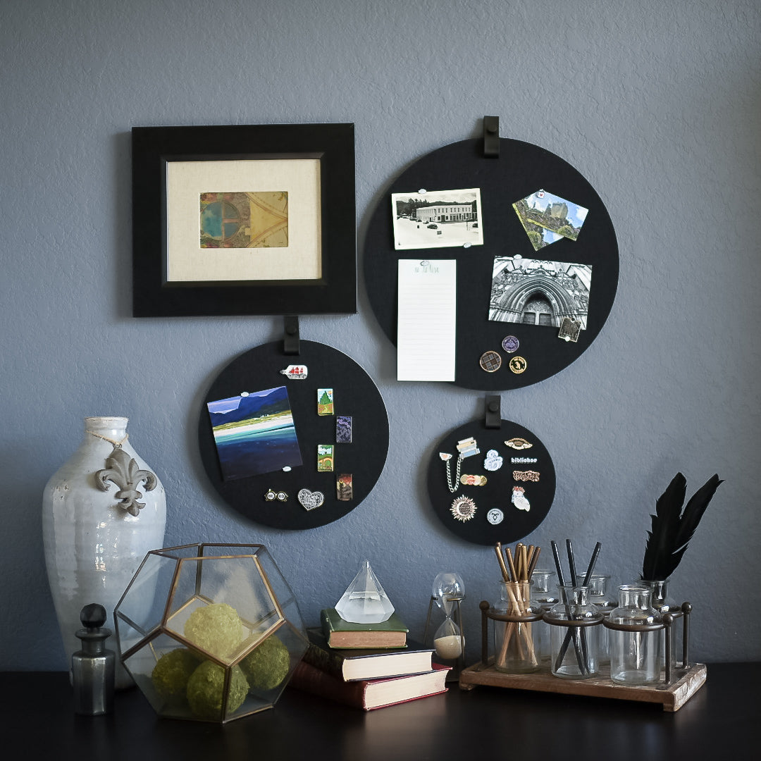 Three round black felt boards with black tabs for organization hanging on a living room wall
