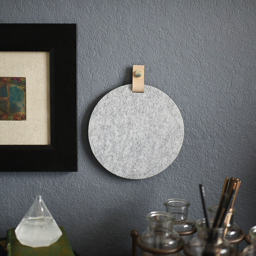Round gray felt board with cream tab for organization hanging on a living room wall