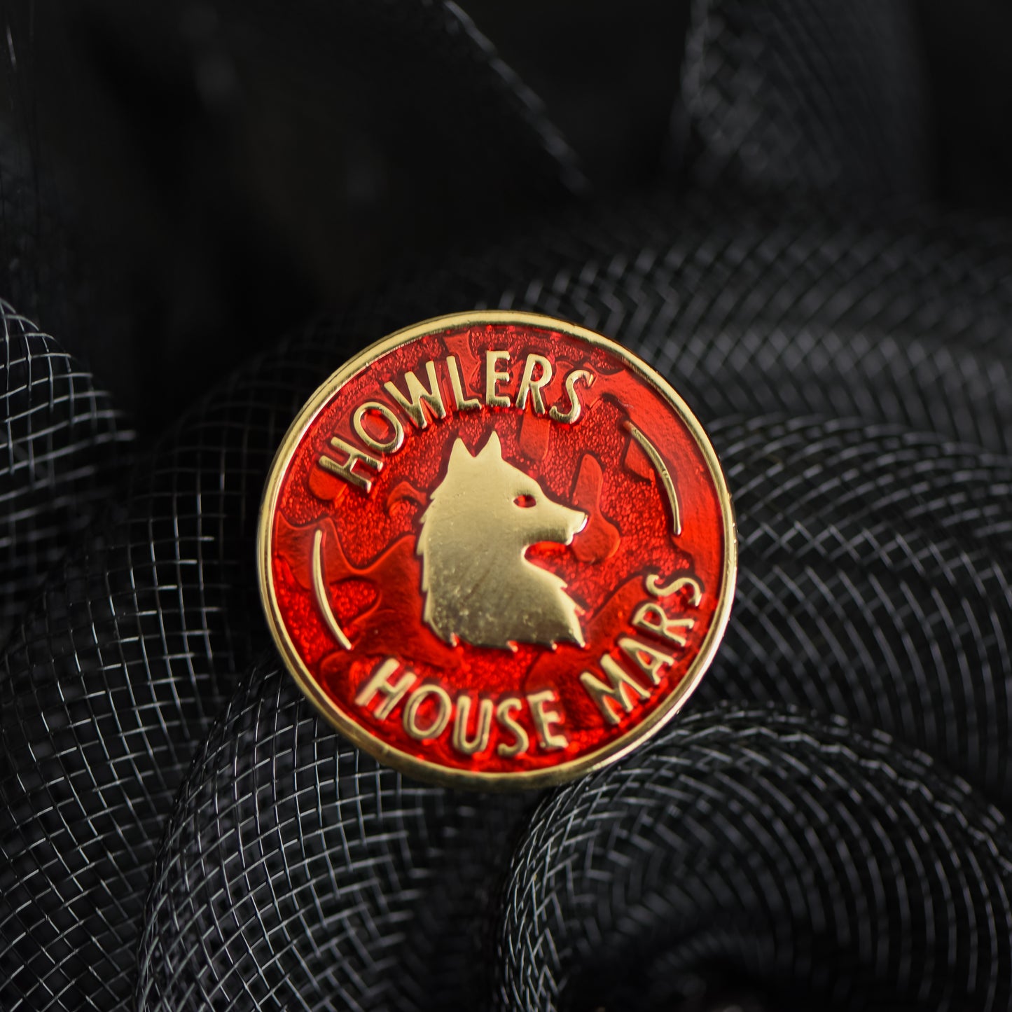 Red and gold circle membership style enamel pin with a wolf and howler house mars text