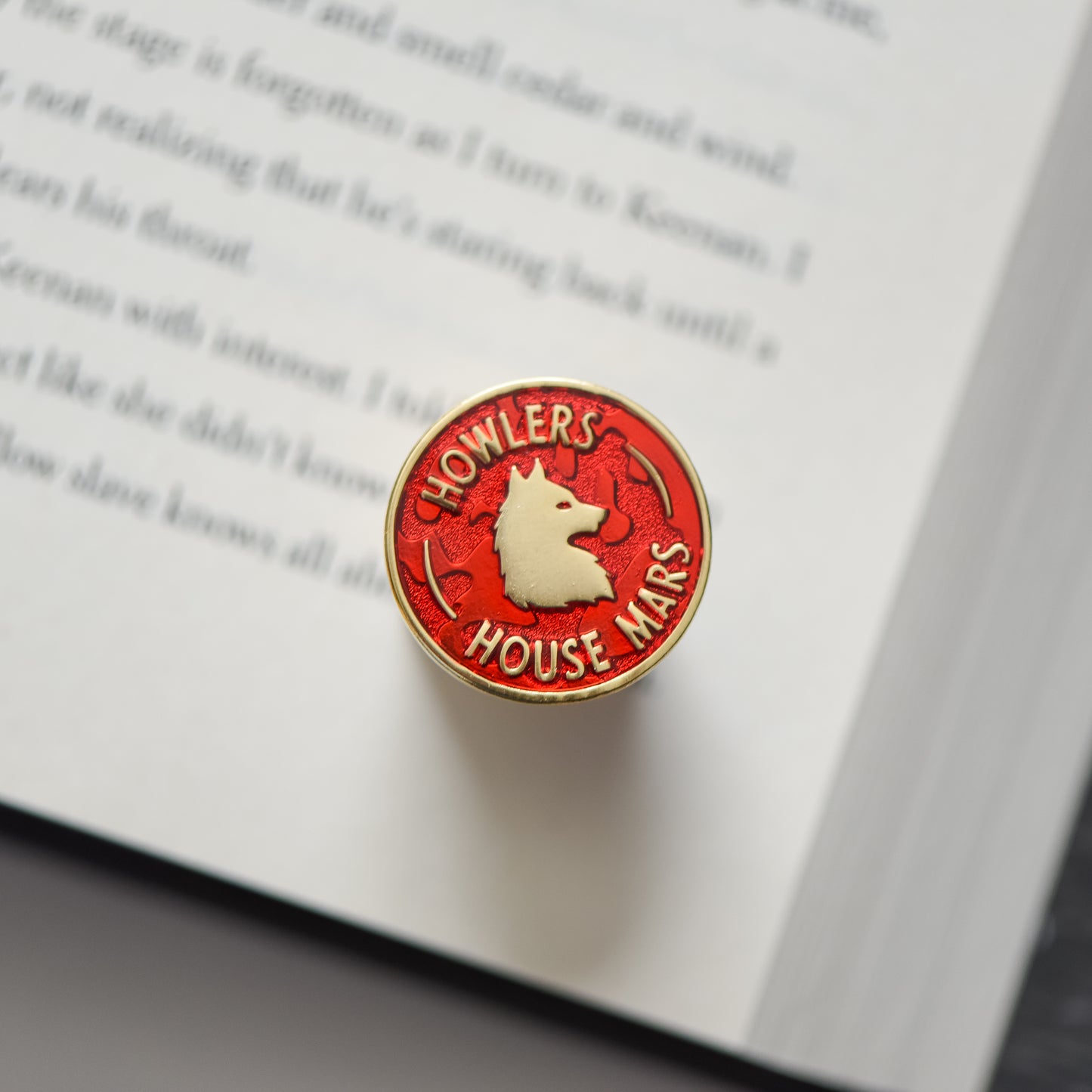 Red and gold circle membership style enamel pin with a wolf and howler house mars text