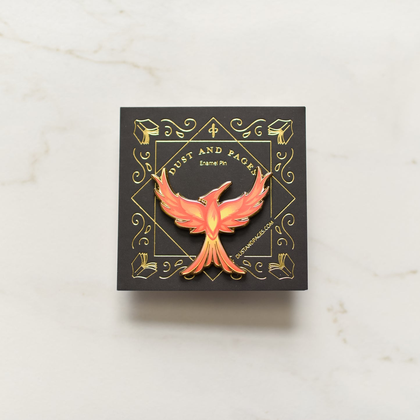 Mockingjay with red orange and yellow flame details enamel pin on a black and gold foil backing card