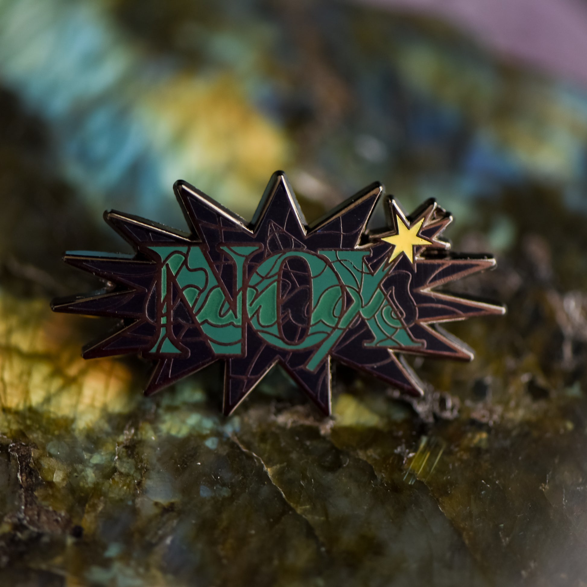 Black nickel enamel pin with Nox in green letters on a potion spell book