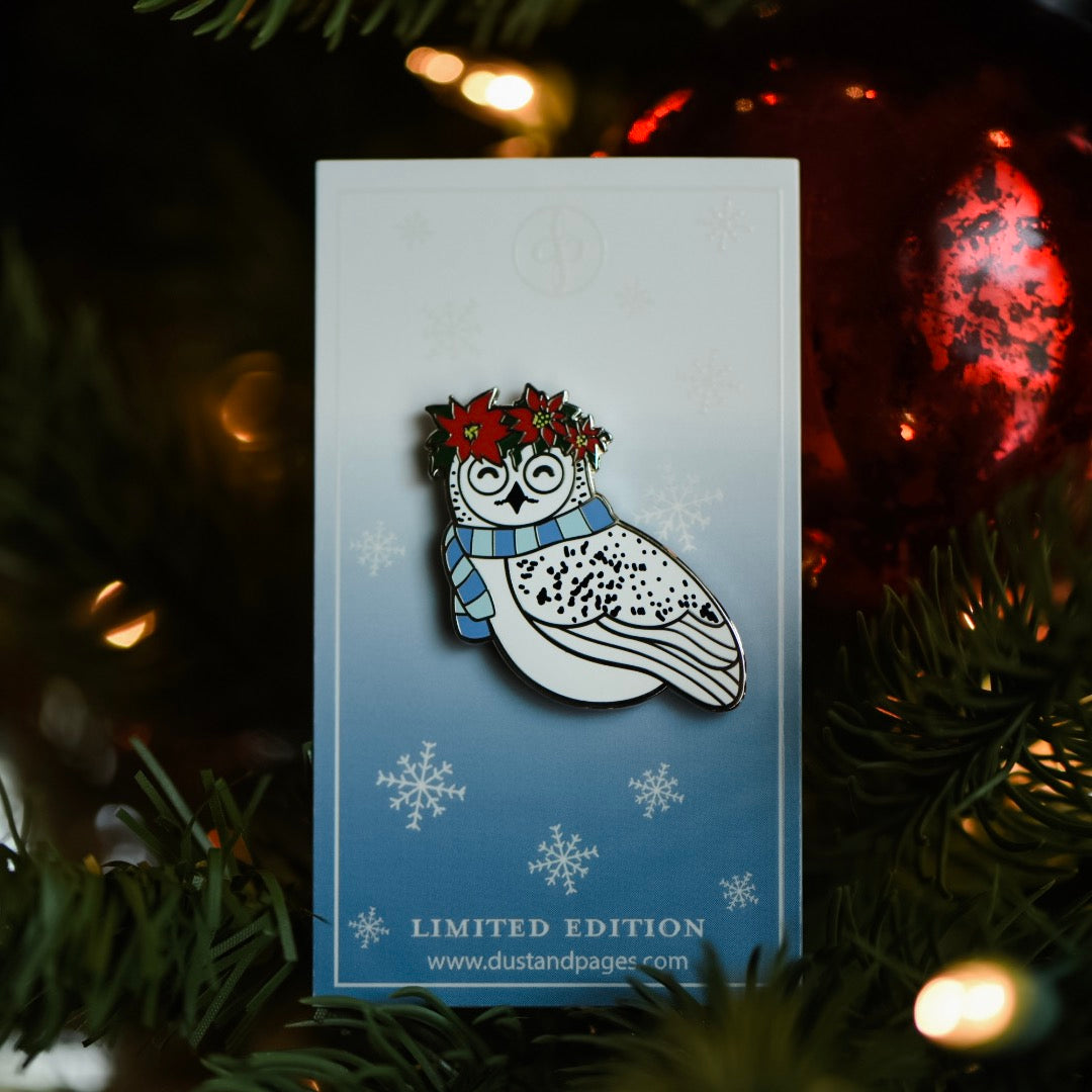 Enamel pin of Hedwig the snowy owl wearing a crown of poinsettias