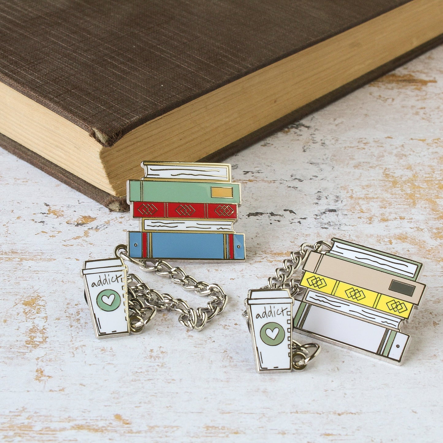 Multi colored stack of books and coffee addict enamel pins