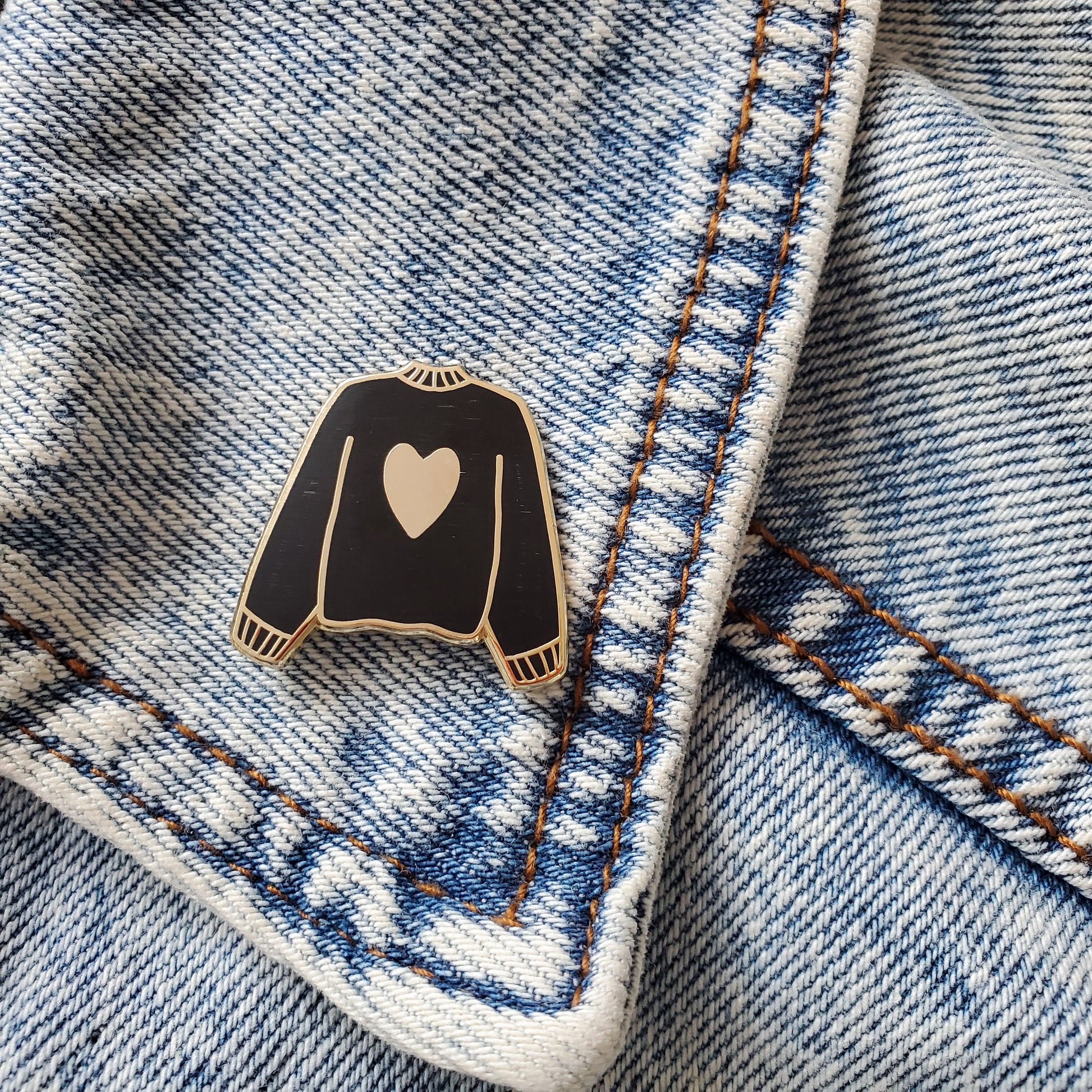 Black hand stamped heart sweater enamel pin on a jean jacket
