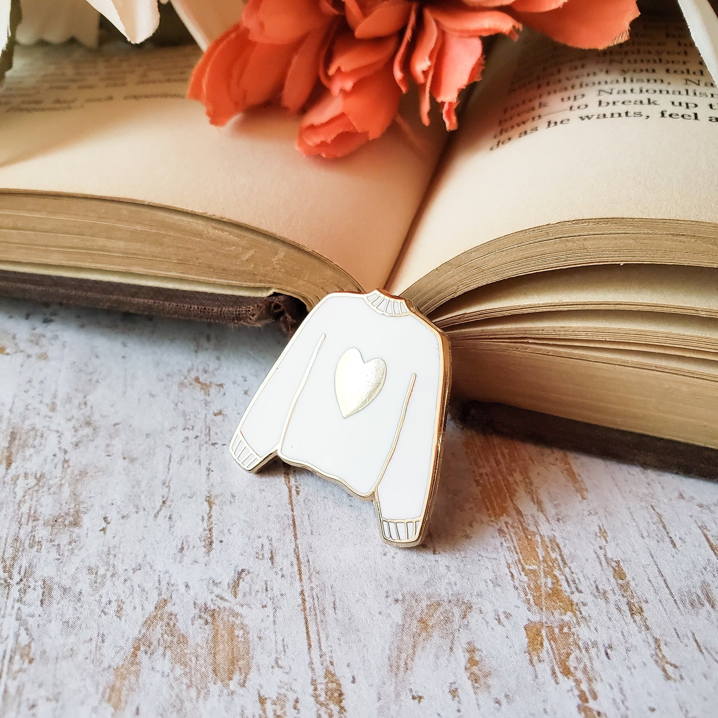 White hand stamped heart sweater enamel pin with a book