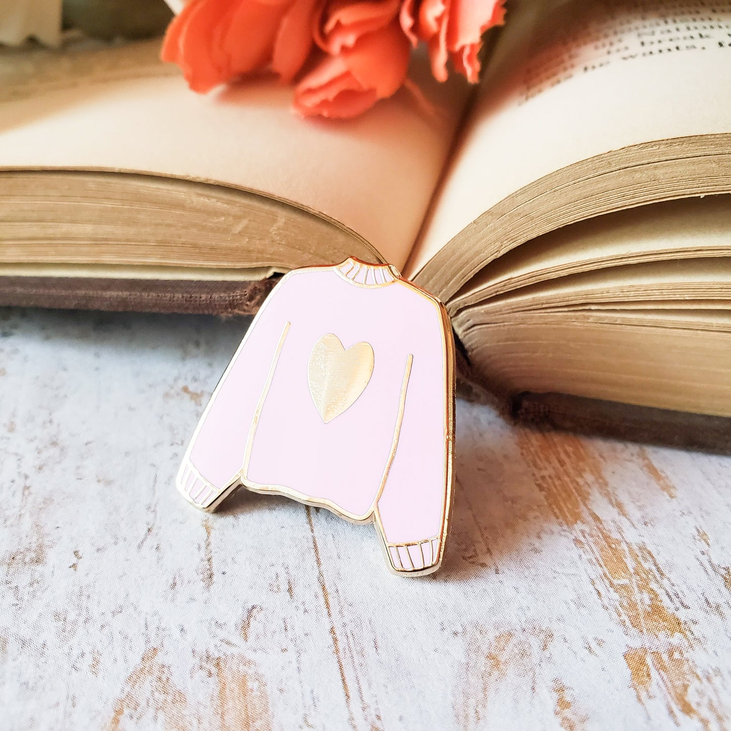 Pink hand stamped heart sweater enamel pin with a book