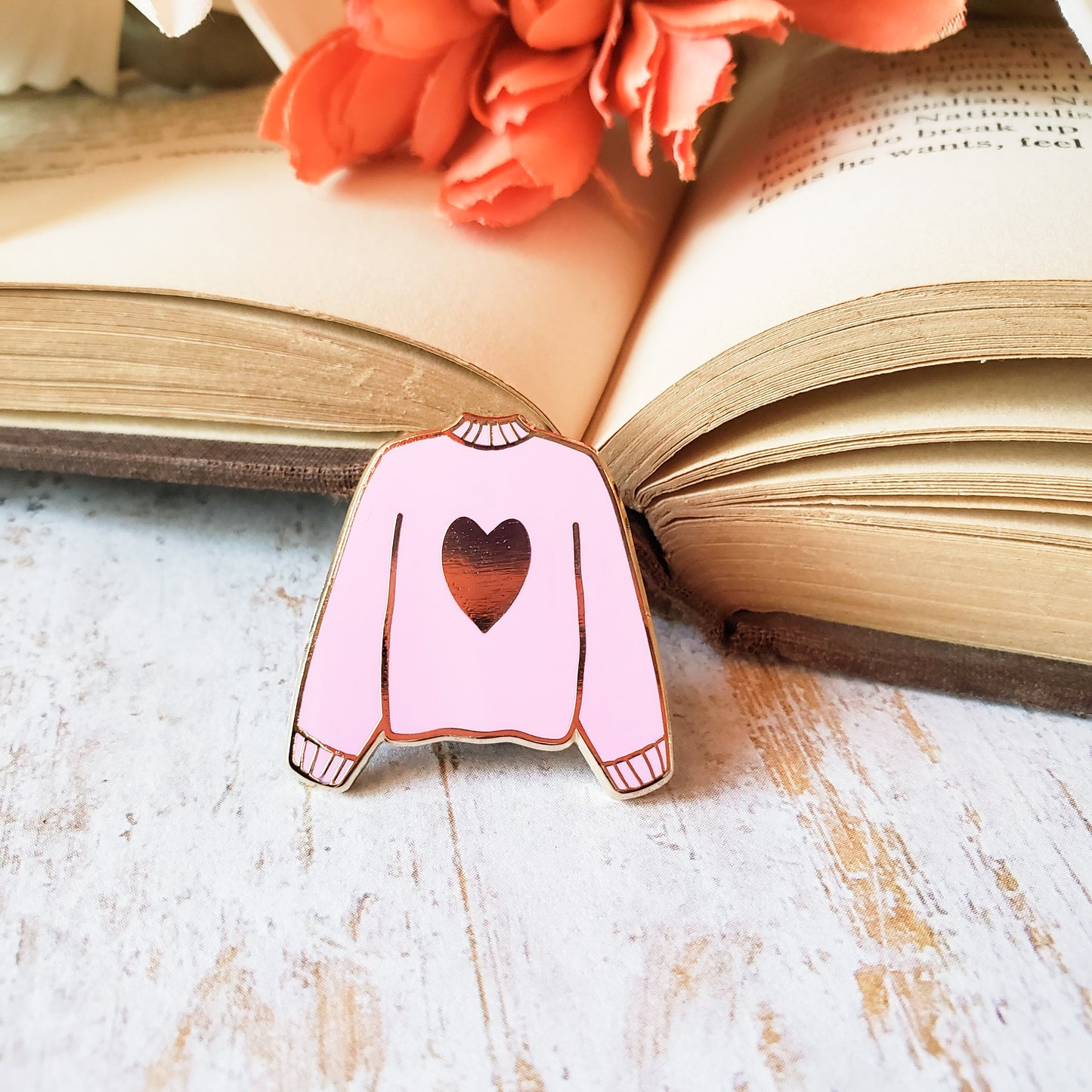 Pink hand stamped heart sweater enamel pin with a book