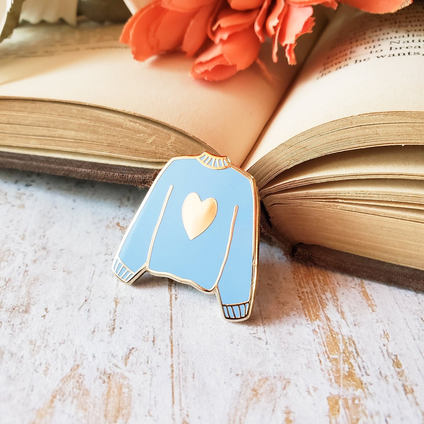 Blue hand stamped heart sweater enamel pin with a book