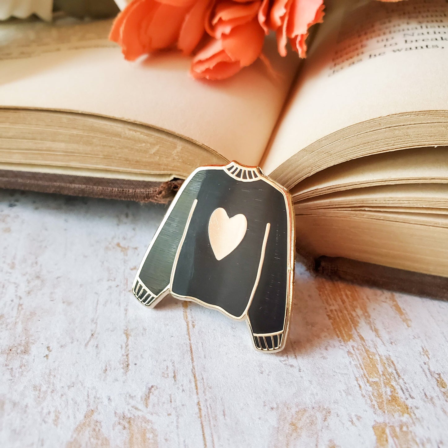 Black hand stamped heart sweater enamel pin with a book